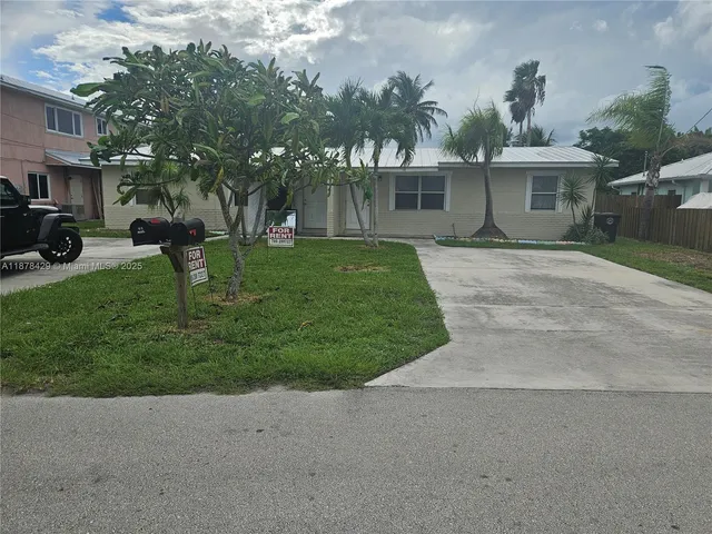 a front view of a house with a garden and trees