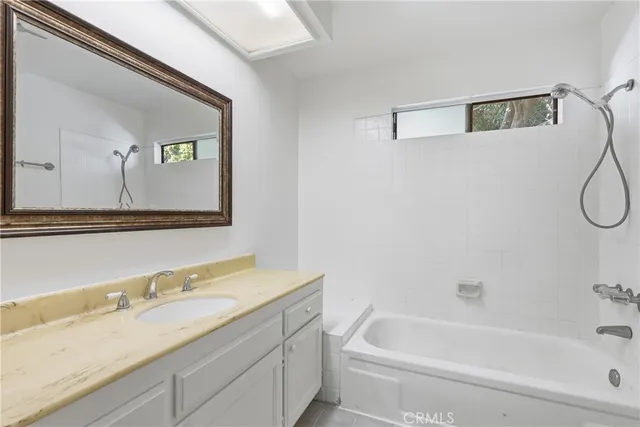 a bathroom with a granite countertop tub sink and mirror