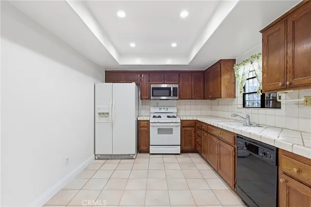 a large kitchen with stainless steel appliances granite countertop a stove top oven a sink and dishwasher