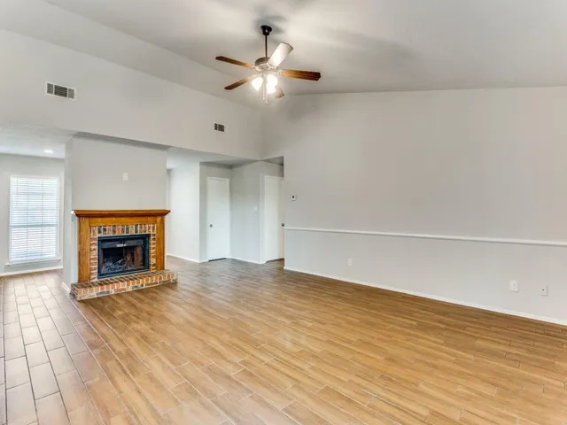 a view of an empty room with a fireplace and a window
