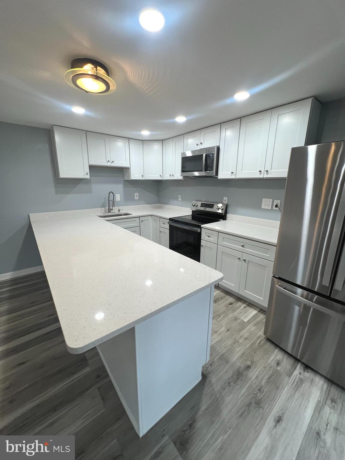 11823 Falls Road Potomac, MD 20854 - Photo 4 of 20 a kitchen with stainless steel appliances granite countertop a sink a stove a refrigerator and island with wooden floor