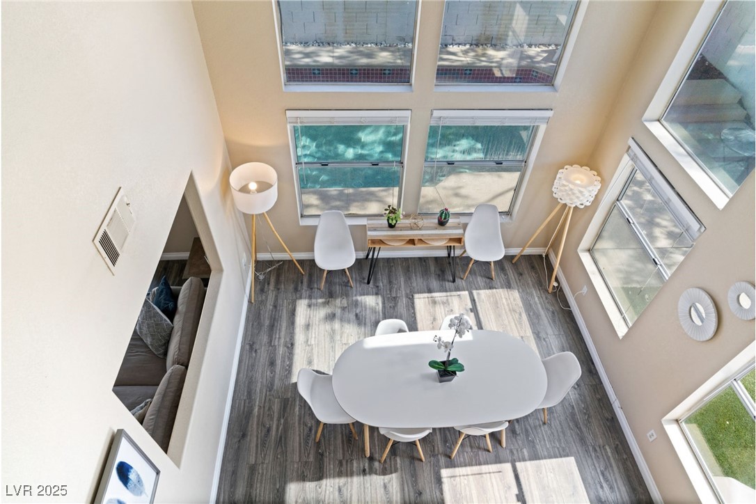 Dining area featuring a high ceiling, wood finished floors, baseboards, and visible vents