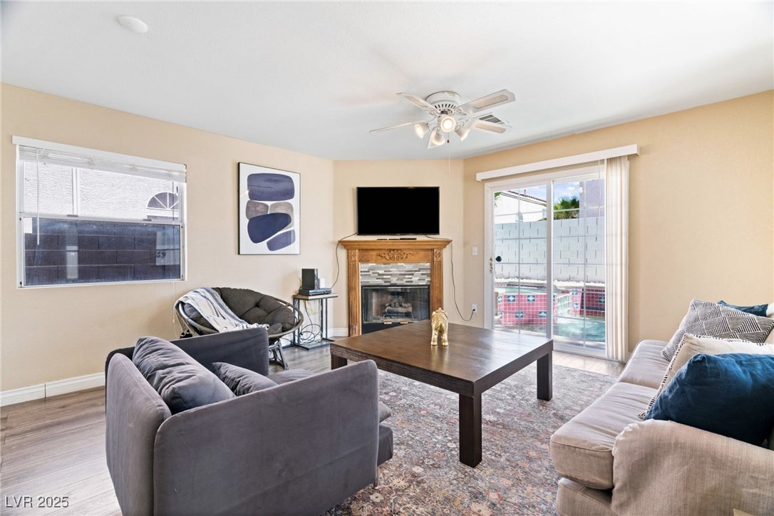 8213 Grassy Point Circle Las Vegas, NV 89145 - Photo 10 of 31 Living area featuring wood finished floors, a high end fireplace, a ceiling fan, and baseboards