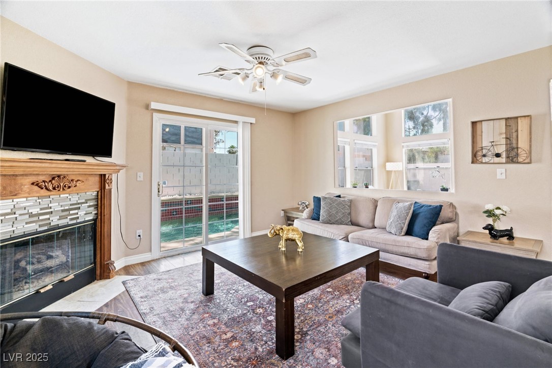 8213 Grassy Point Circle Las Vegas, NV 89145 - Photo 11 of 31 Living room featuring light wood finished floors, a fireplace with flush hearth, baseboards, and ceiling fan
