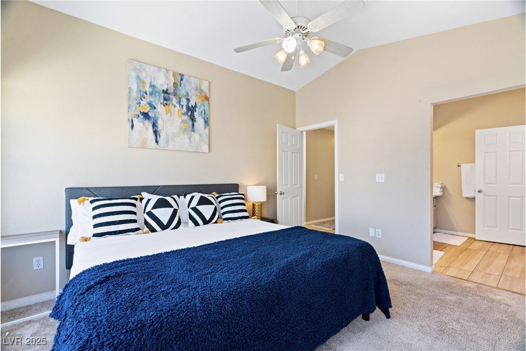 8213 Grassy Point Circle Las Vegas, NV 89145 - Photo 15 of 31 Carpeted bedroom with baseboards, a ceiling fan, ensuite bath, and lofted ceiling