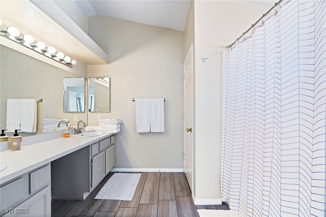 8213 Grassy Point Circle Las Vegas, NV 89145 - Photo 18 of 31 Bathroom with vanity, baseboards, curtained shower, and wood finished floors