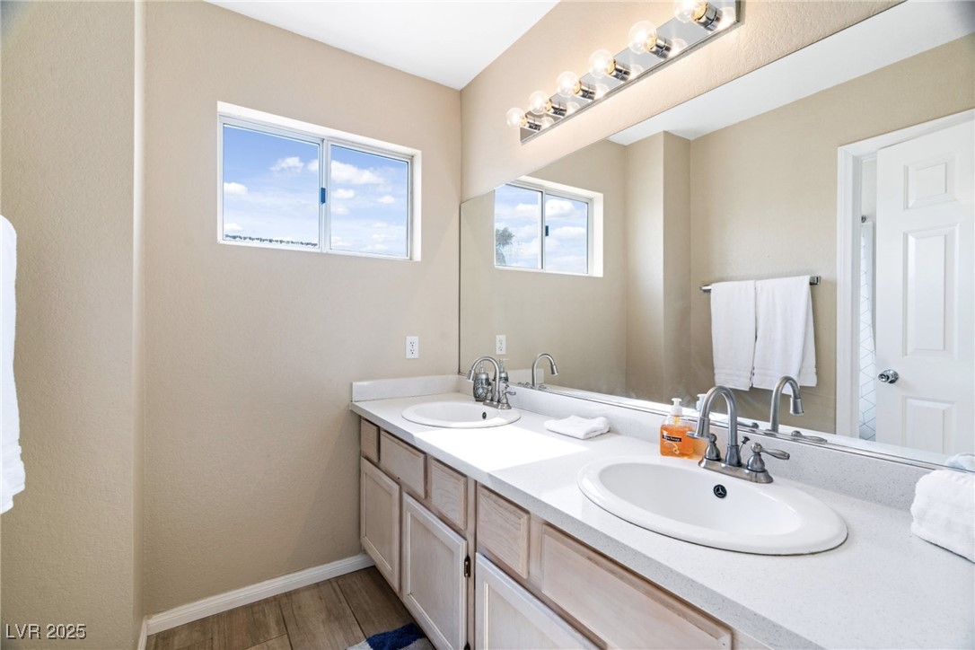 8213 Grassy Point Circle Las Vegas, NV 89145 - Photo 21 of 31 Full bathroom with a sink, baseboards, double vanity, and wood finished floors