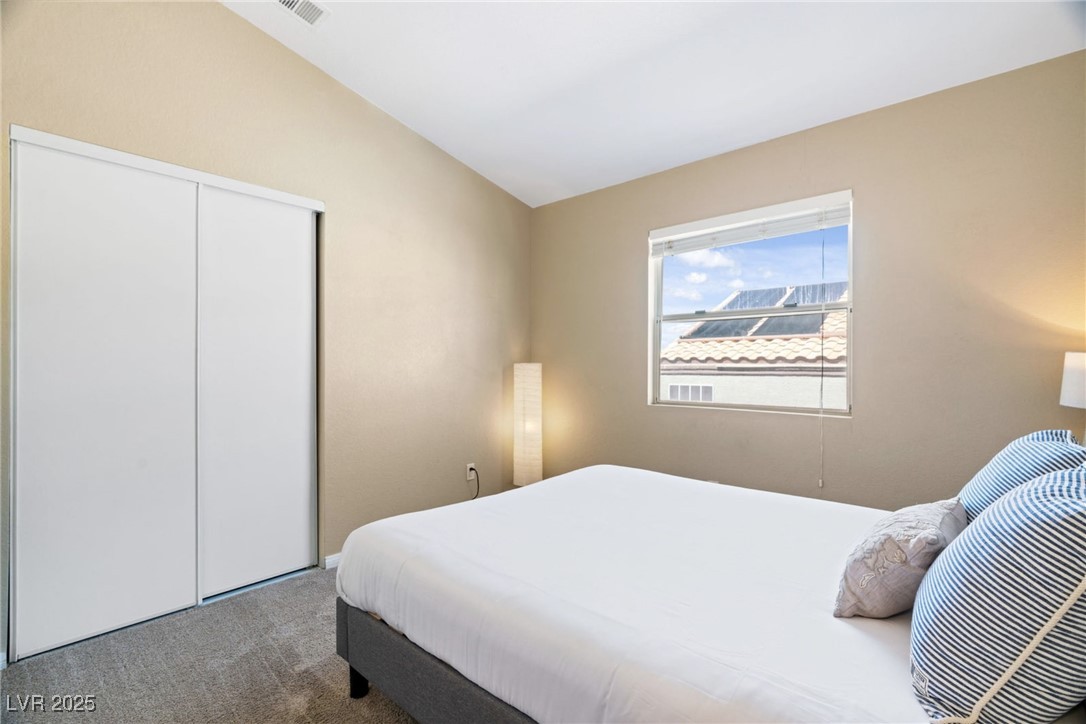 8213 Grassy Point Circle Las Vegas, NV 89145 - Photo 25 of 31 Bedroom featuring a closet, carpet flooring, visible vents, and lofted ceiling