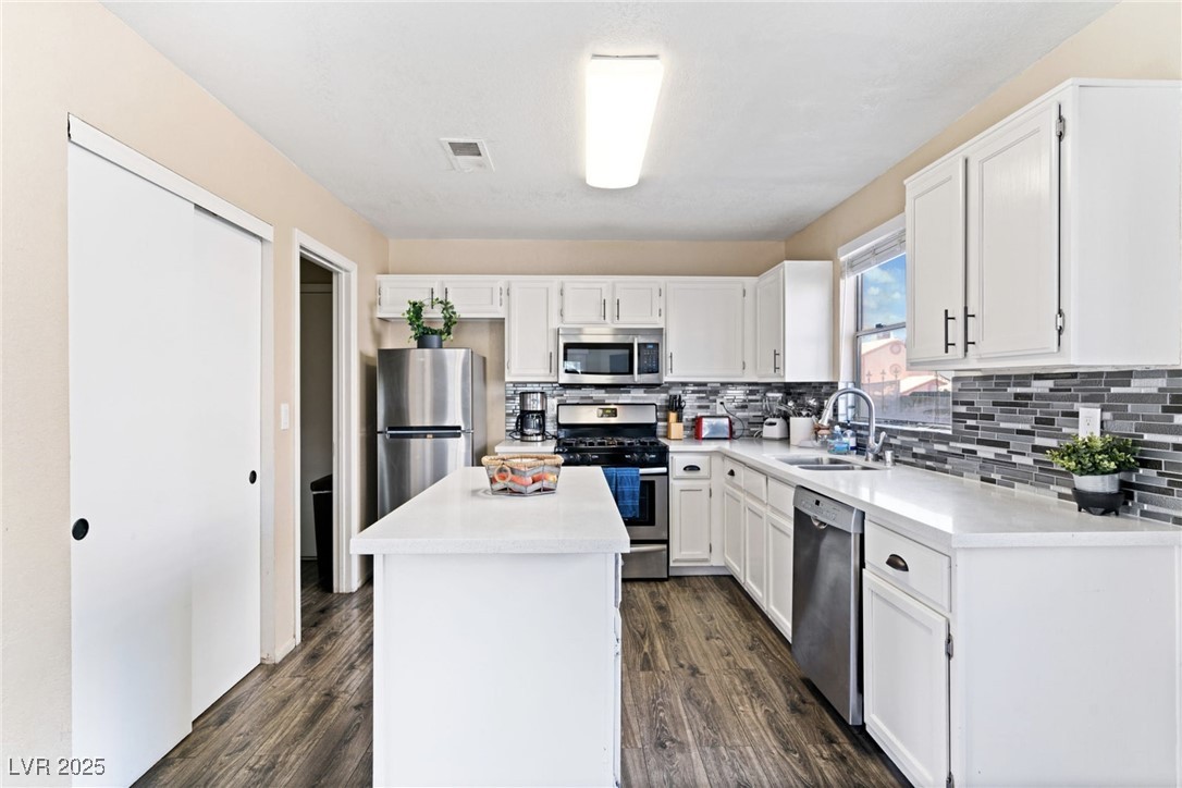8213 Grassy Point Circle Las Vegas, NV 89145 - Photo 7 of 31 Kitchen featuring a sink, tasteful backsplash, appliances with stainless steel finishes, and white cabinetry