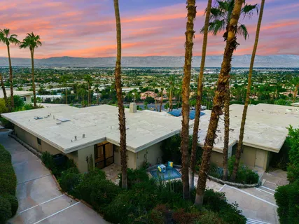 a view of a house with a yard and potted plants