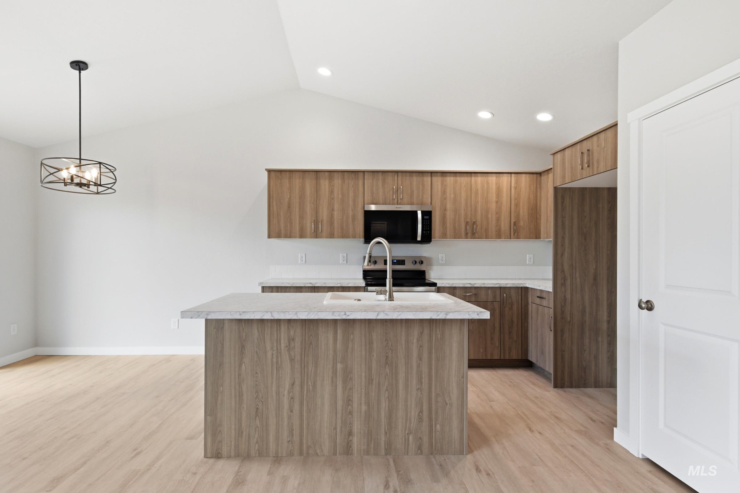 16632 North Shorthorn Loop Nampa, ID 83651 - Photo 3 of 17 Kitchen featuring an island with a built-in sink, wood-finish cabinetry, light-toned countertops, and stainless steel appliances