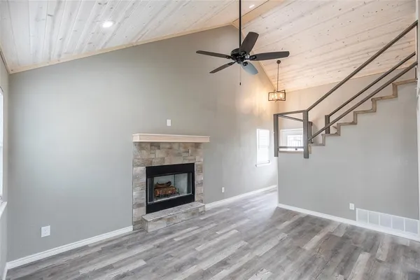 a view of an empty room with wooden floor fireplace and a window