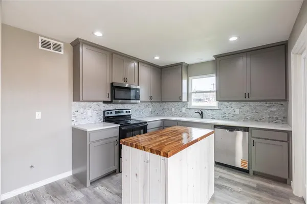 a kitchen with a sink stove top oven and refrigerator