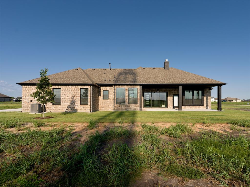 2108 Charters Circle Nevada, TX 75173 - Photo 32 of 37 Back of house with a lawn, brick siding, a shingled roof, and a patio area