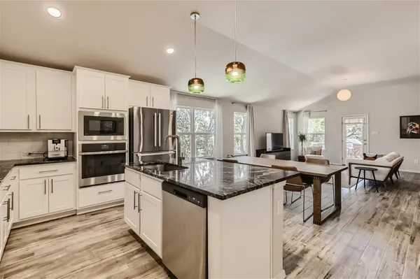 a kitchen with stainless steel appliances granite countertop a stove a sink and a microwave