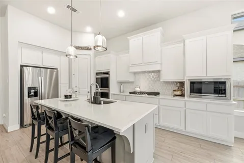 a kitchen with stainless steel appliances a table chairs stove and refrigerator
