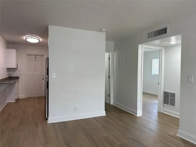 a view of a kitchen with a refrigerator and wooden floor