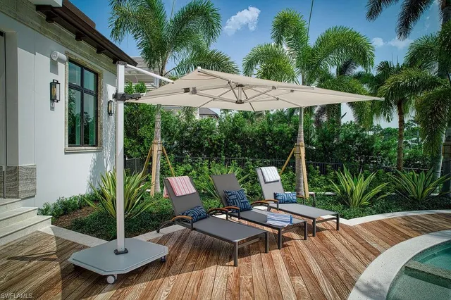 a view of a white house with a big yard plants and large trees