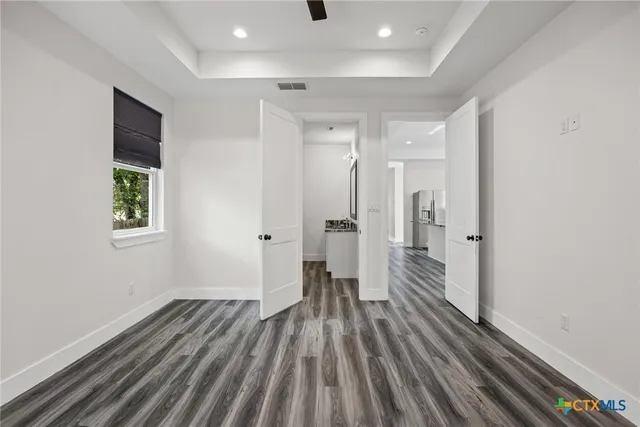 a view of a room with wooden floor a ceiling fan and a window
