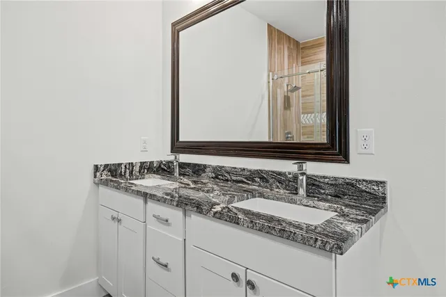 a bathroom with a granite countertop sink and a mirror