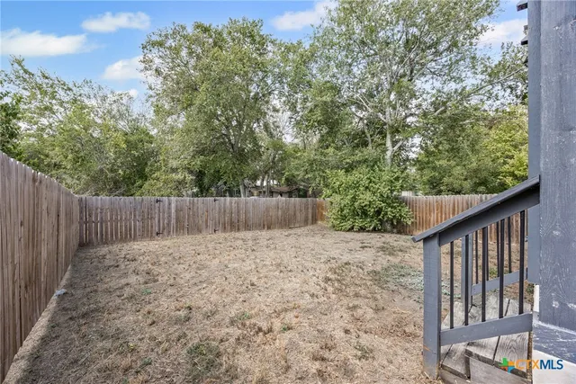 a view of a backyard with wooden fence and trees