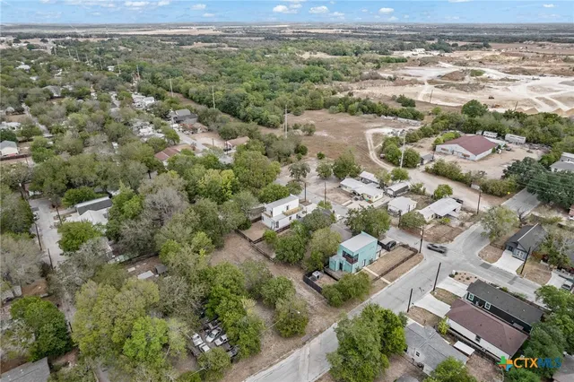 an aerial view of residential houses with outdoor space and trees