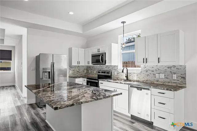 a kitchen with stainless steel appliances granite countertop a sink stove and refrigerator