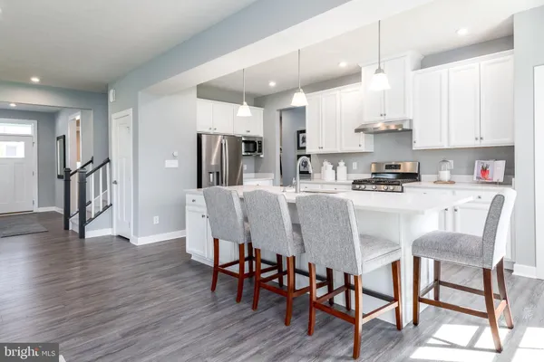 a kitchen with stainless steel appliances granite countertop a dining table chairs refrigerator and microwave