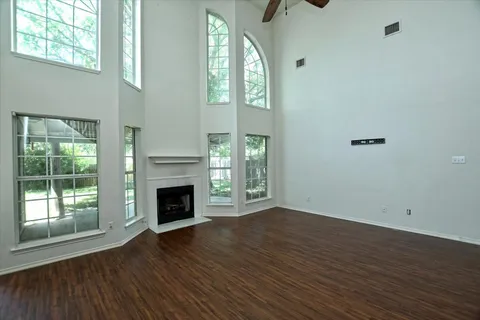 an empty room with wooden floor fireplace and windows