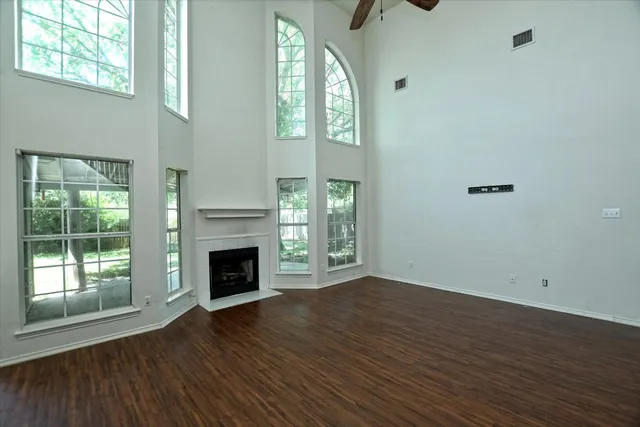 an empty room with wooden floor fireplace and windows