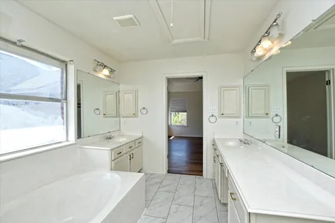 a spacious bathroom with a tub sink shower and mirror