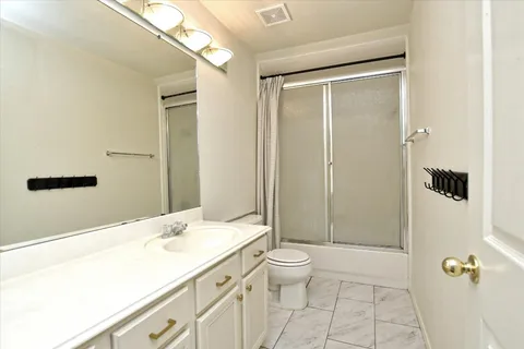 a bathroom with a granite countertop sink a toilet and shower