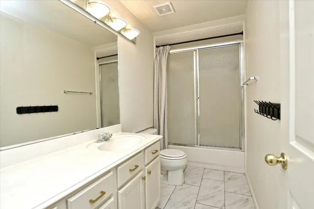 a bathroom with a granite countertop sink a toilet and shower