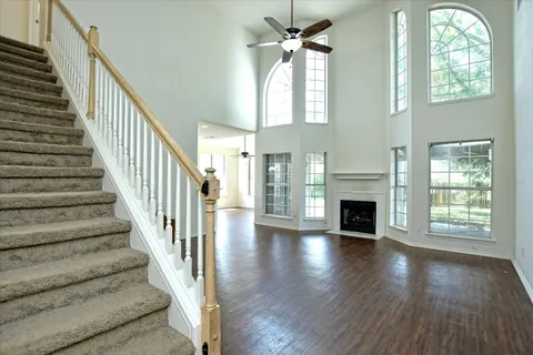a view of an empty room with wooden floor fireplace and a window