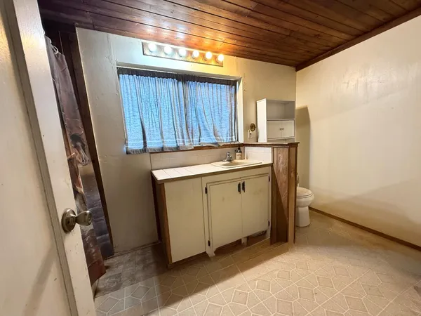 a utility room with a sink a cabinetry and a window