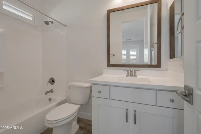 a bathroom with a toilet a sink a mirror a vanity and shower