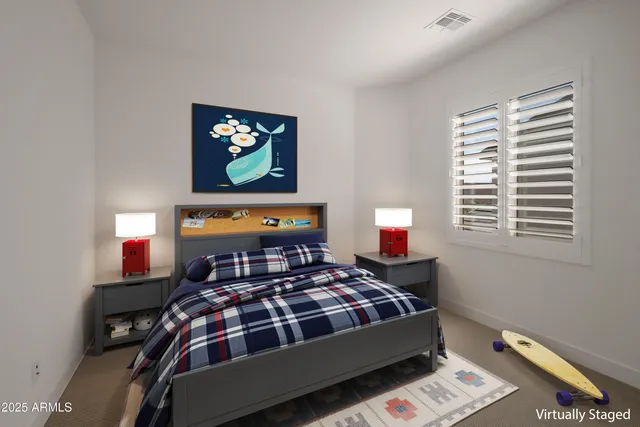 a bedroom with a bed and a lamp on dresser