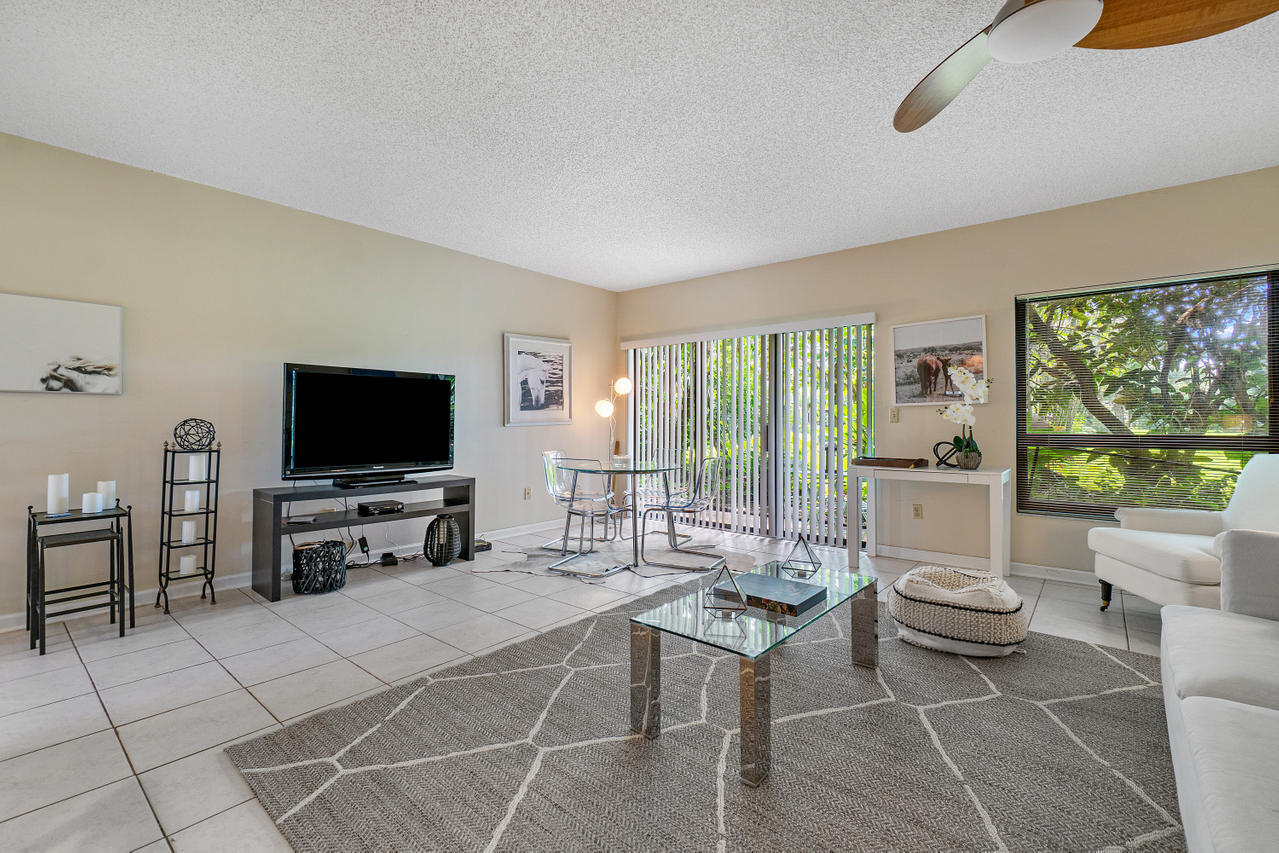 13334 Polo Club Road, Unit 238 Wellington, FL 33414 - Photo 2 of 13 a living room with furniture a flat screen tv and a floor to ceiling window