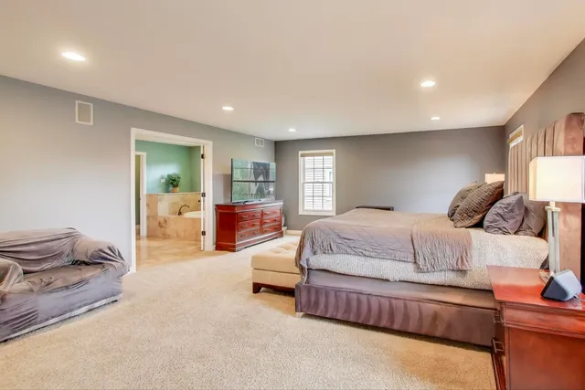 a spacious bedroom with a bed and wooden floor
