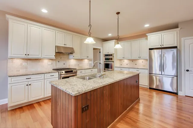 a kitchen with a refrigerator a sink and wooden floor