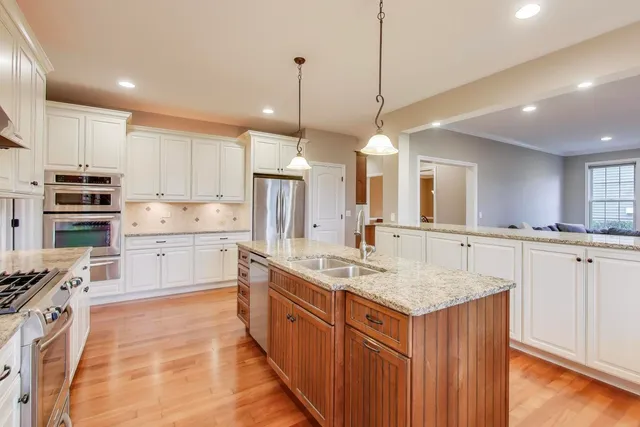 a kitchen with kitchen island granite countertop a sink appliances and cabinets