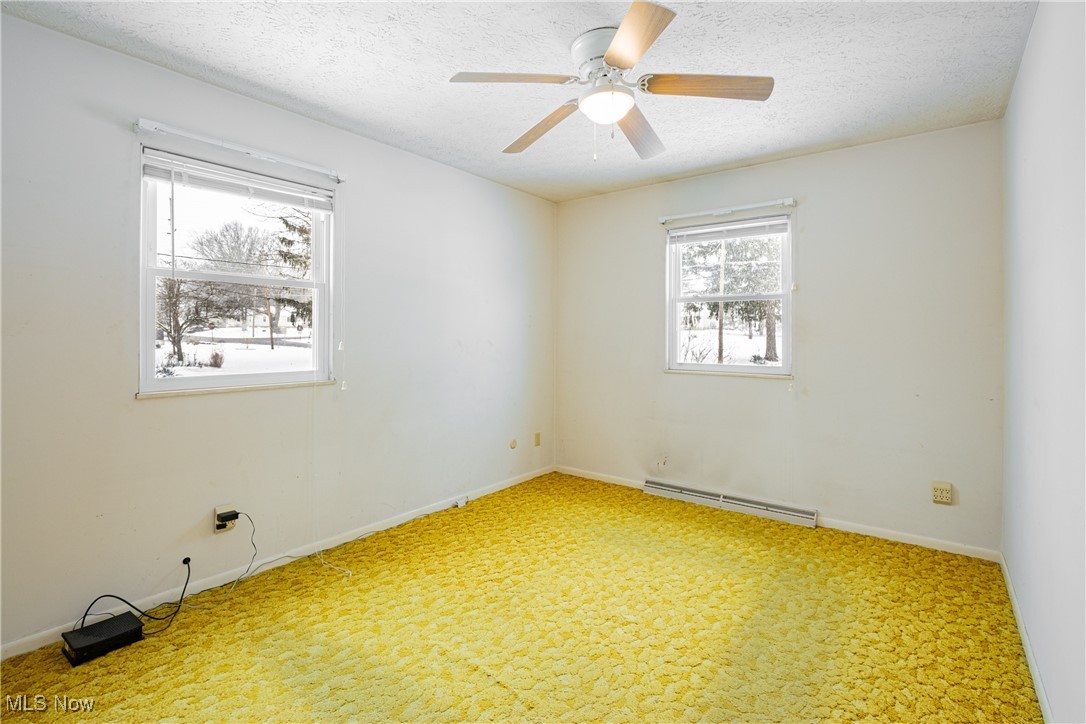 5905 Renninger Road New Franklin, OH 44319 - Photo 13 of 31 Spare room with ceiling fan, carpet, a textured ceiling, and a baseboard heating unit