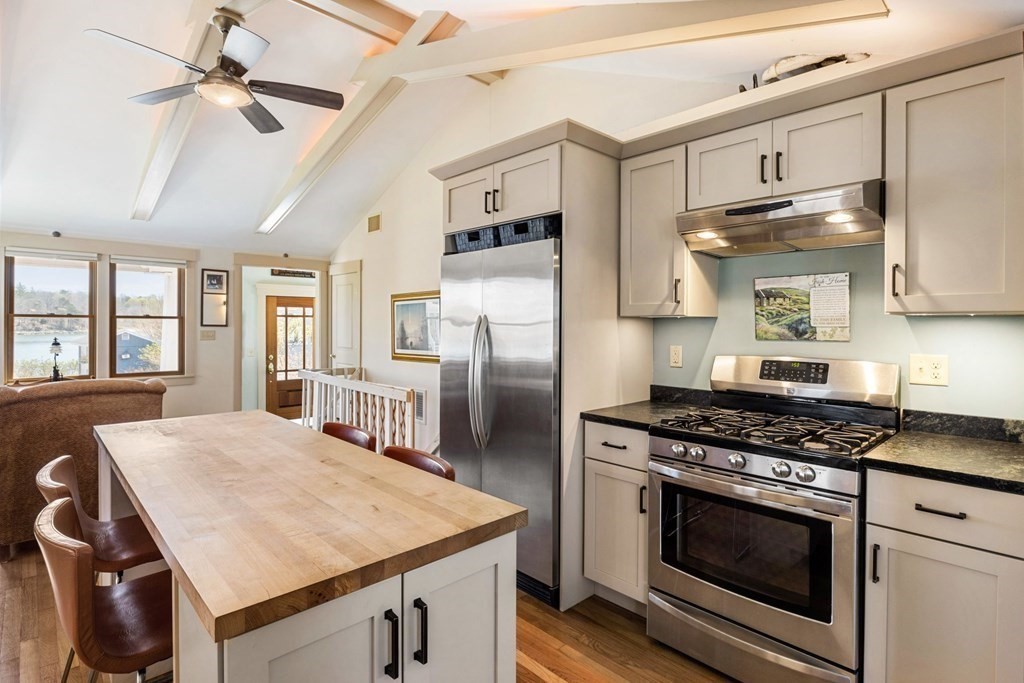 238 Nantasket Road Hull, MA 02045 - Photo 9 of 29 a kitchen with stainless steel appliances a stove a refrigerator a sink a stove white cabinets and couches with wooden floor