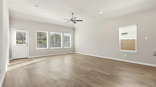 a view of an empty room with a window and wooden floor
