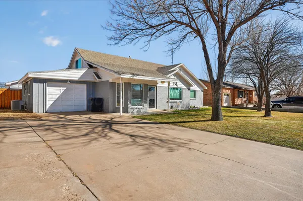 a view of a house with a yard and large tree