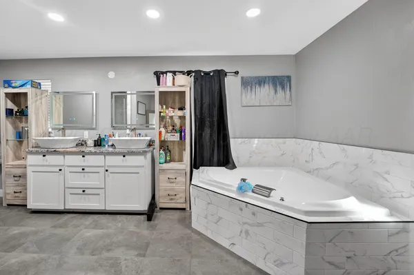 a bathroom with a bathtub sink and a large mirror