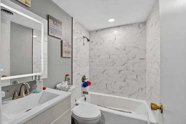 a bathroom with a bathtub shower sink vanity mirror and toilet