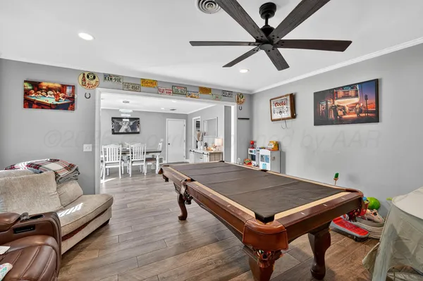 a living room with furniture pool table and a ceiling fan