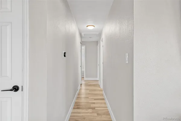 a view of a hallway with wooden floor and a bathroom