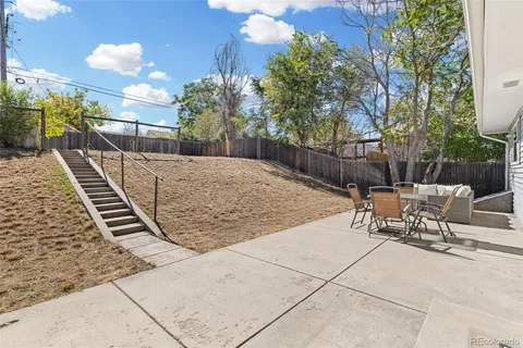 a view of backyard with outdoor seating and wooden fence
